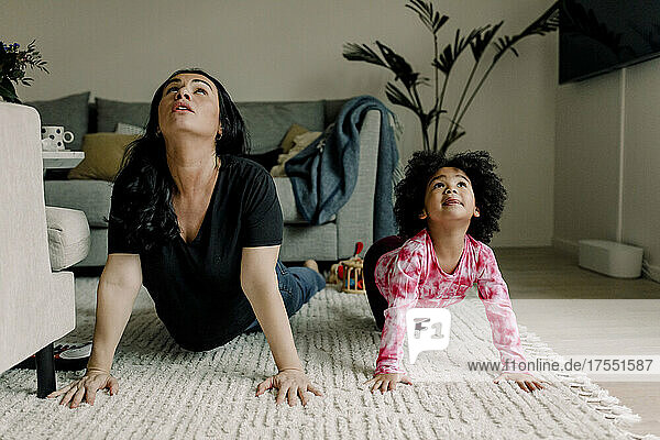 Mutter und Tochter üben Yoga im Wohnzimmer zu Hause