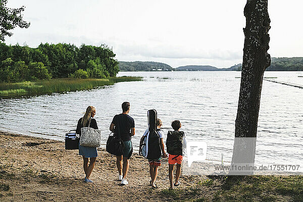 Rear view of family walking towards beach during weekend