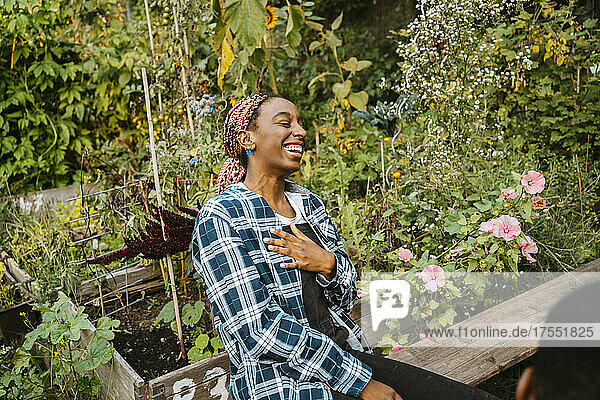 Fröhliche junge Frau  die lachend in einem städtischen Bauernhof sitzt