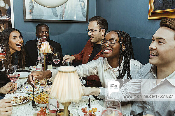 Multirassische weibliche und männliche Freunde beim Essen am Tisch im Restaurant