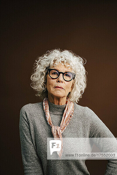 Porträt einer älteren Frau mit Brille auf braunem Hintergrund