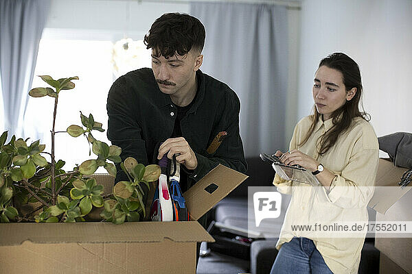 Ein junges Paar betrachtet einen Karton beim Umzug in eine neue Wohnung