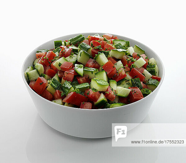Mediterraner Tomaten-Gurken-Salat in Schüssel vor weißem Hintergrund