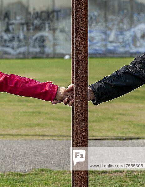 Symbolbild Grenze  Soziale Distanz  Freundschaftlicher Handschlag zwischen rostigen Eisenstangen hindurch  Berlin  Deutschland  Europa
