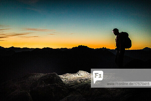 Silhouetted view of backpacker on mountain summit.
