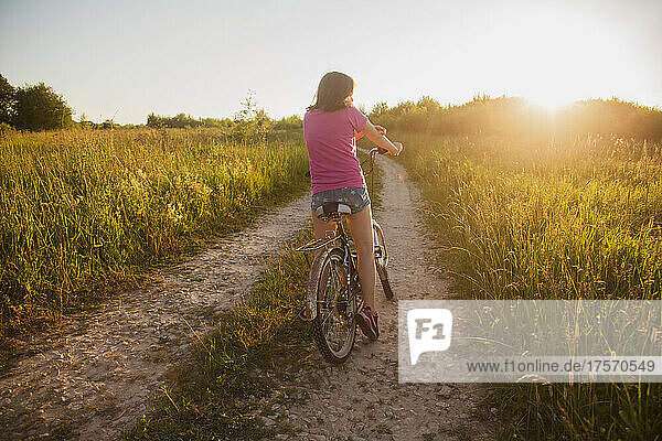 Teenage girl on an old bike in the field