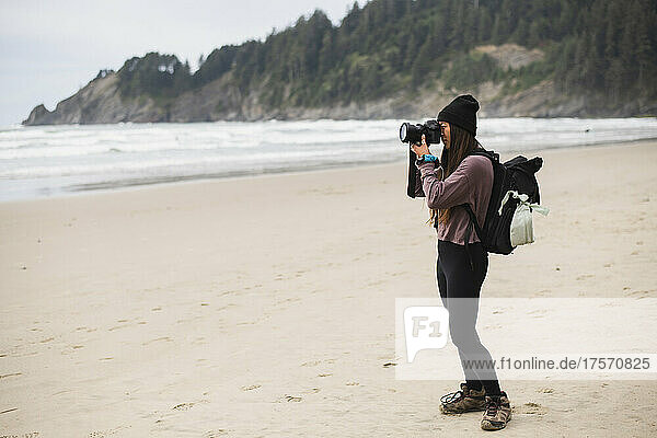 Young Woman taking photograph alone on Oregon beach