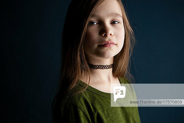 Portrait of a cute and serious little girl on dark background