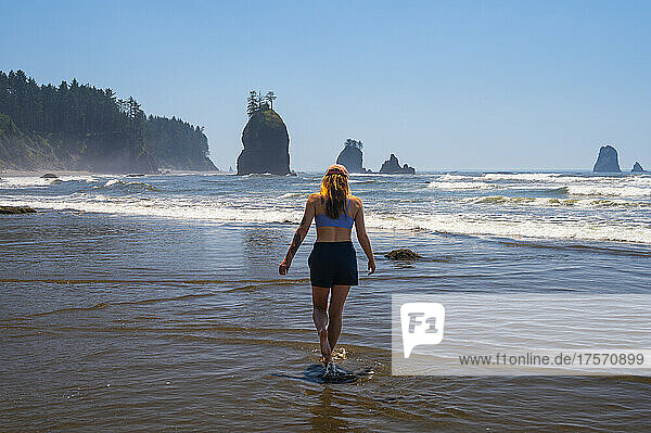 Female walking in the shallow water of the olympic coast beach