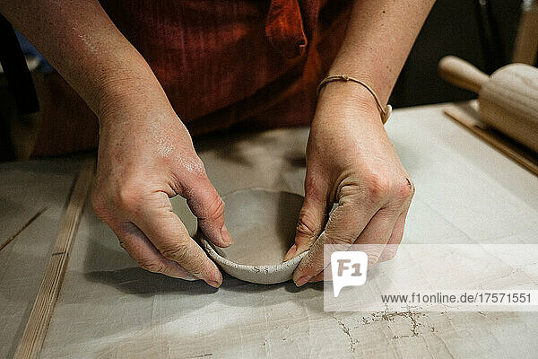 Woman's hands works with clay on the table