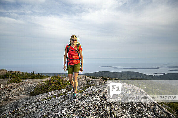 Fit woman hikes along summit of mountain  Acadia National Park  Maine
