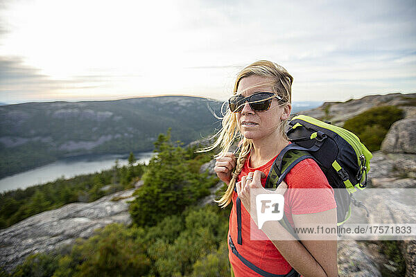 Healthy woman with sunglasses hikes on mountain summit  Maine