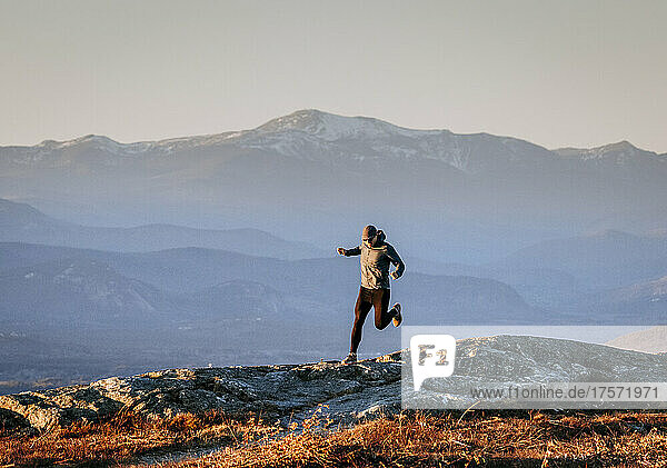 Male trail runner runs along summit of Foss Mountain  New Hampshire