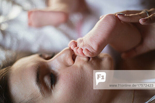 young mother kissing her baby's foot