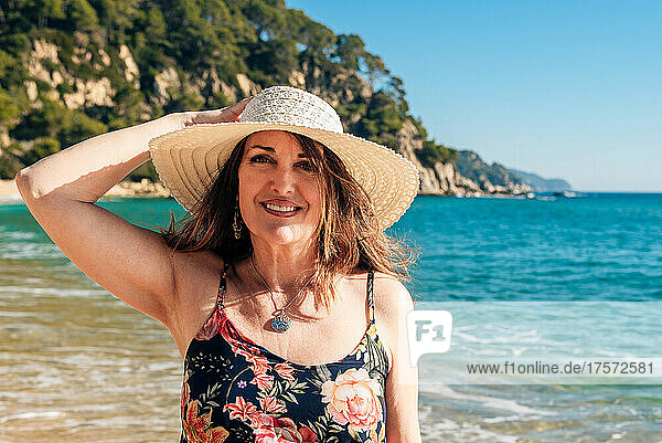 50 year old woman walking with a hat on a beach