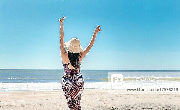 Frau mit Hut von hinten am Strand  junge Frau hebt ihre Hände am Strand. Rivas  Nicaragua  Mittelamerika