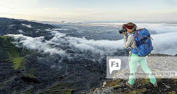 Hiker photographs spectacular landscape  fog on cliffs and glacier Myrdalsjökull  Pakgil  Iceland  Europe