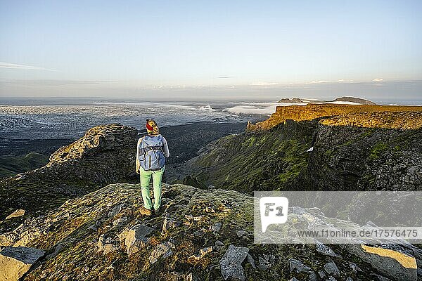 Hiker looks over spectacular landscape  cliffs and glacier Myrdalsjökull  Pakgil  Iceland  Europe