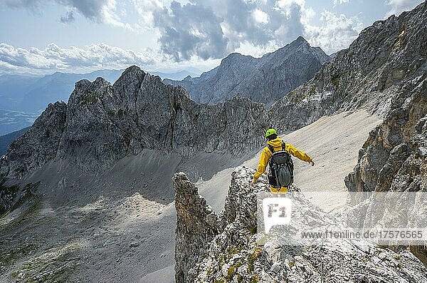 Wanderer balanciert auf Felsvorsprung  Wanderweg zur Lamsenspitze  hinten Kar und felsige Berggipfel mit Mitterkarlspitze  Karwendelgebirge  Alpenpark Karwendel  Tirol  Österreich  Europa
