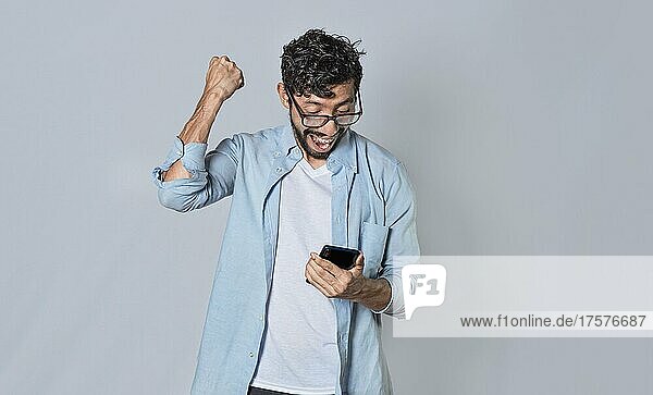 Glücklicher Mann hält ein Smartphone und feiert  aufgeregter Mann schaut auf sein Smartphone