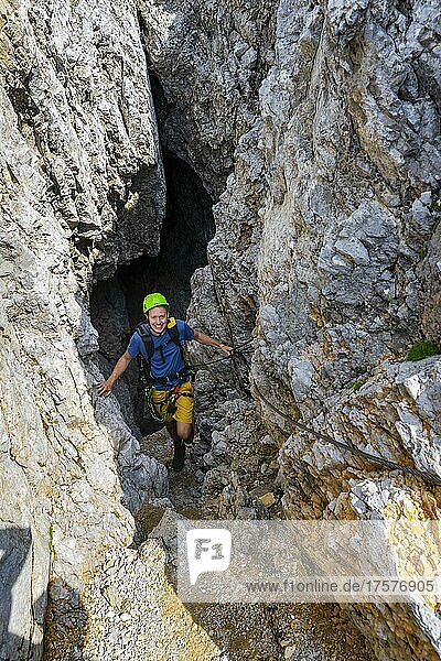 Young man climbing out of a rock hole  via ferrata Brudertunnel  Karwendel Mountains  Alpenpark Karwendel  Tyrol  Austria  Europe