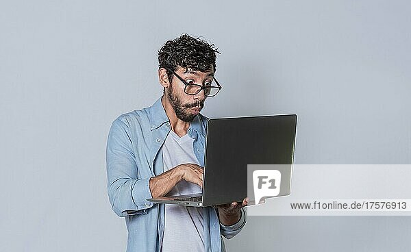 Gut aussehender Mann seinen Laptop isoliert  überrascht Mann seinen Laptop zu überprüfen  Kerl mit Laptop