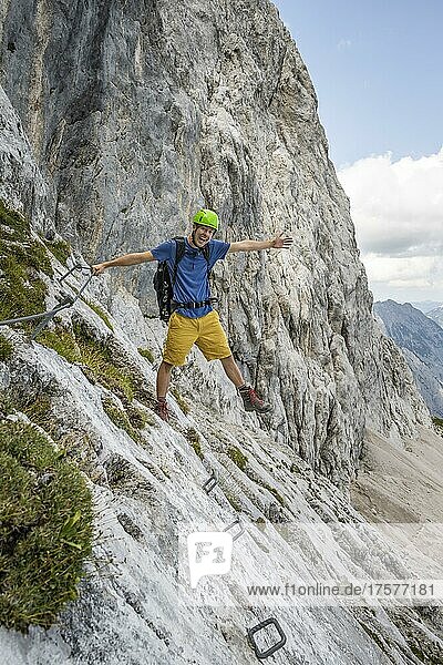 Young man stretching out his arms and legs  climbing on a via ferrata  hiking trail to the Lamsenspitze  Karwendel Mountains  Alpenpark Karwendel  Tyrol  Austria  Europe