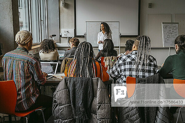Female professor teaching university students in classroom