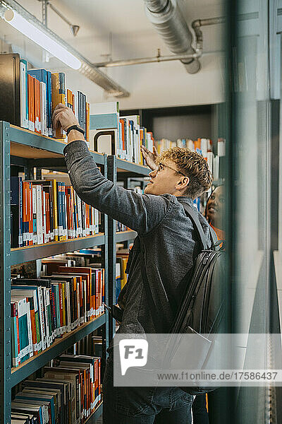 Junge Studenten suchen gemeinsam ein Buch in der Universitätsbibliothek
