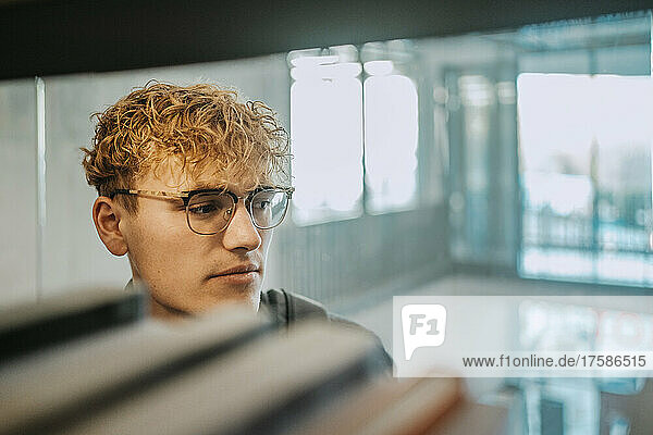 Junger Mann mit Brille in der Bibliothek einer Universität