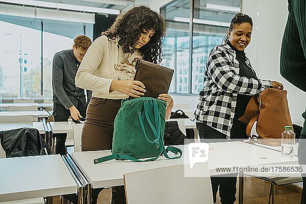 Multirassische Studenten packen Rucksack im Klassenzimmer des Community College