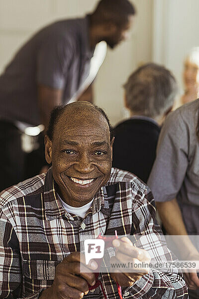 Portrait of smiling elderly man knitting at retirement home