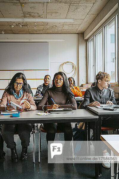 Multirassische Universitätsstudenten sitzen am Schreibtisch und lernen im Klassenzimmer
