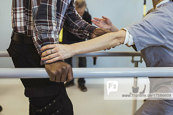 Midsection of female caregiver helping senior man to walk at retirement home