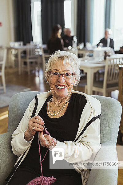 Porträt einer lächelnden älteren Frau  die im Pflegeheim strickt
