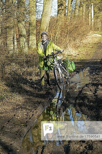 Frau macht Radtour mit E-Bike über schlammigen Waldweg und durch Pfützen  Lüneburg  Niedersachsen  Deutschland  Europa