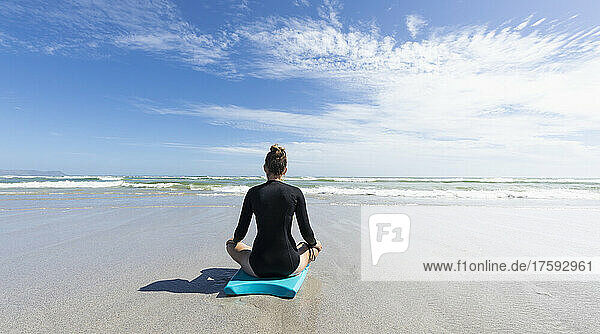 Girl (16-17) meditating on body board at Grotto Beach