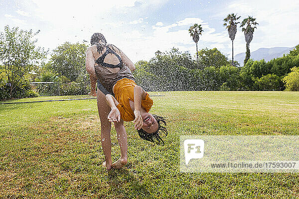 South Africa  Western Cape  Stanford  Girl (16-17) and boy (8-9) playing with water on lawn