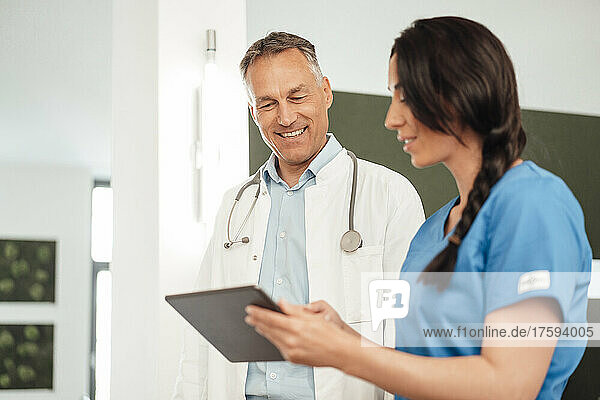 Nurse discussing with smiling doctor over tablet PC in hospital