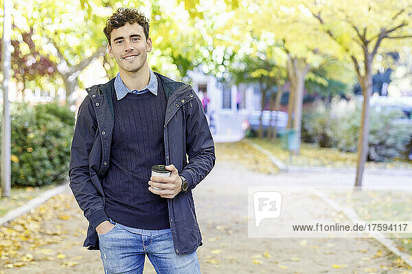 Smiling man with disposable coffee cup in college park