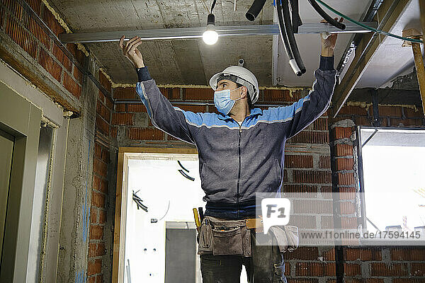 Worker measuring breadth with steel rod at construction site