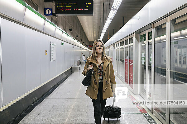 Woman with wheeled luggage at underground subway station