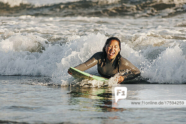 Fröhliche Frau surft inmitten einer Welle im Meer  Gran Canaria  Kanarische Inseln