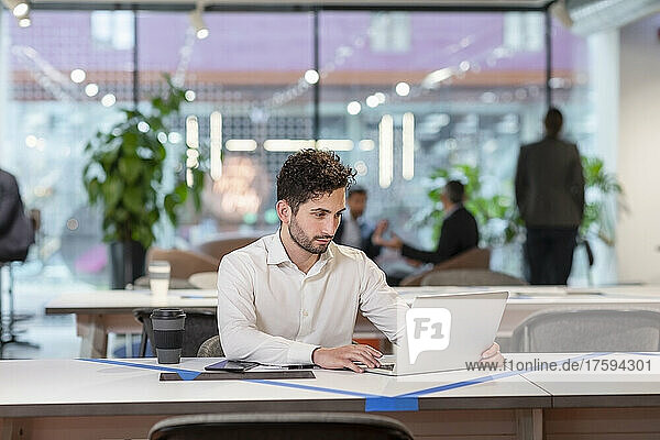 Businessman working over laptop at desk in office