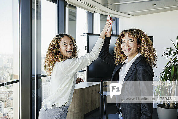 Happy businesswomen giving high five to each other at office
