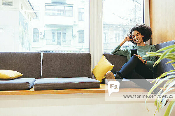 Smiling businesswoman using smart phone on sofa
