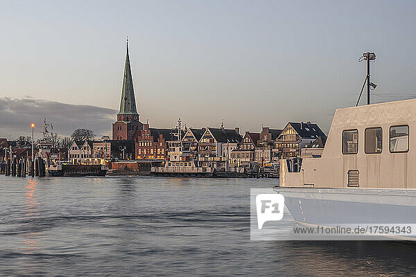 Germany  Schleswig-Holstein  Lubeck  Skyline of Travemunde at dusk with ferry in foreground