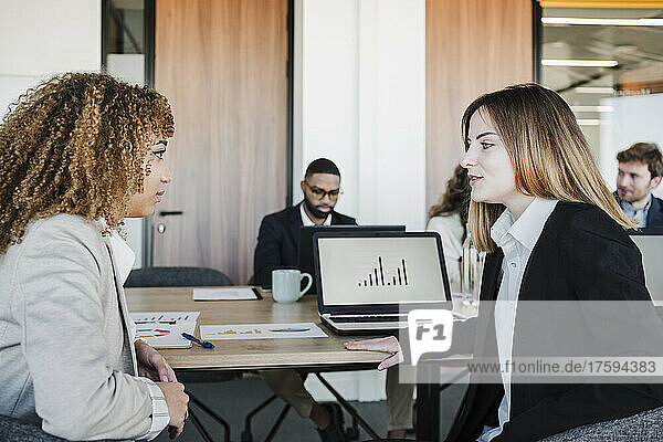 Young businesswoman discussing with colleague in office