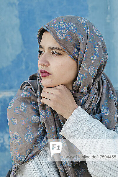 Thoughtful young woman in hijab in front of wall