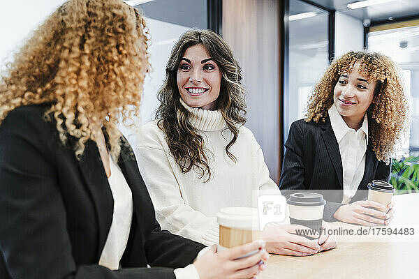 Businesswomen talking to each other at coffee break in coworking office